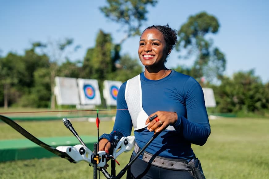 woman holding archery bow standing infront of arhcery targets